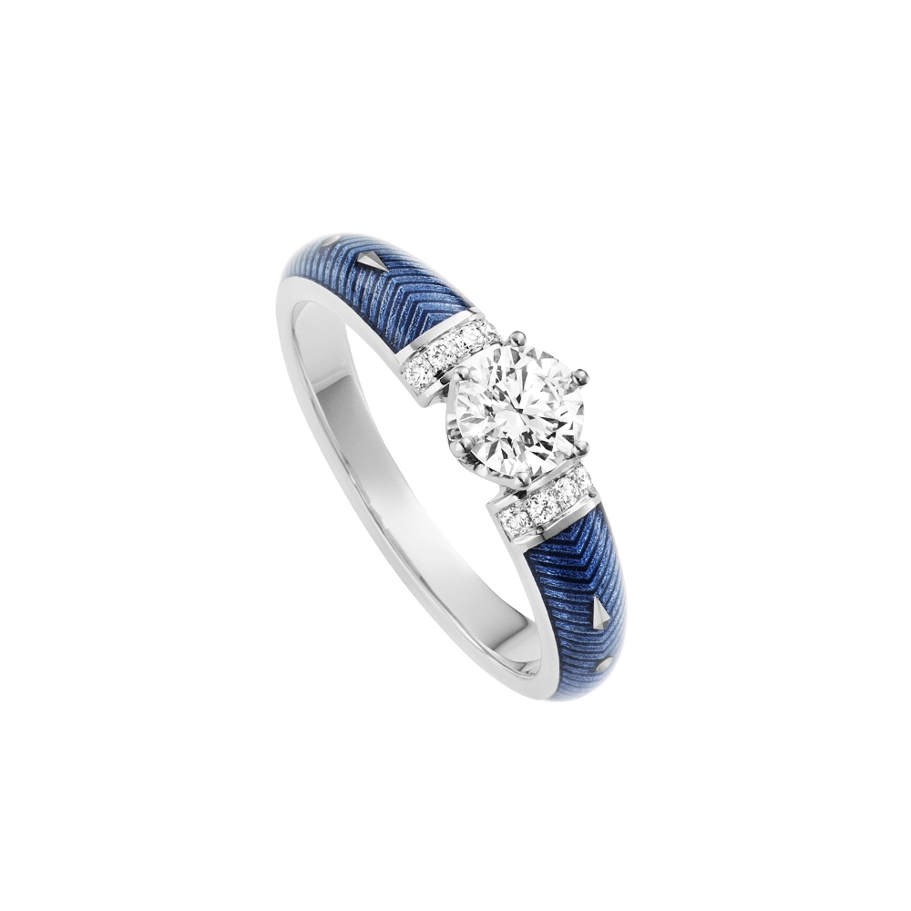 Goldener Ring mit einem weißen Mittelstein und zwei Reihen kleiner Diamanten daneben. Die Ringschultern sind hellblau gefärbt.