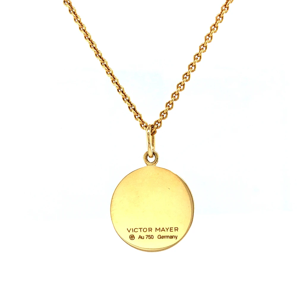 Kleiner runder Anhänger aus Gelbgold, etwa so groß wie eine kleine Münze. Die Vorderseite schimmert in opalisierendem Weiß, das im Licht wie ein Opal die Farben changieren lässt. Ein feines Wellenmuster wird unter der Emaille sichtbar.