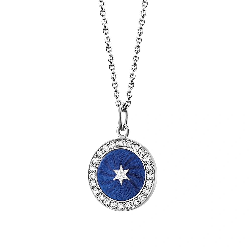 Kleiner runder Anhänger aus Weißgold, etwa so groß wie eine kleine Münze. Die Vorderseite schimmert Electric blue in durchscheinender Emaille mit feinem Wellenmuster. In der Mitte ist ein winziges sechseckiges Goldplättchen in Sternform eingelassen, umrahmt von 24 funkelnden Brillanten.