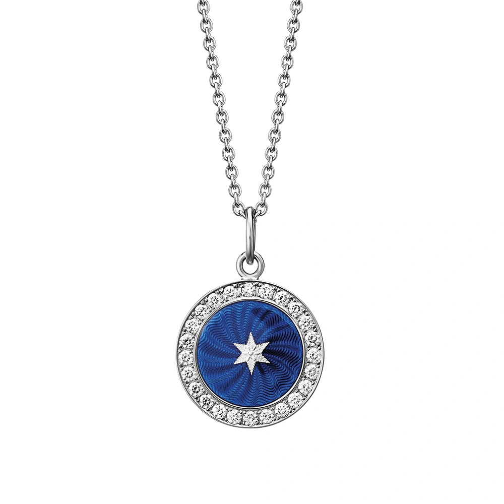 Kleiner runder Anhänger aus Weißgold, etwa so groß wie eine kleine Münze. Die Vorderseite schimmert Electric blue in durchscheinender Emaille mit feinem Wellenmuster. In der Mitte ist ein winziges sechseckiges Goldplättchen in Sternform eingelassen, umrahmt von 24 funkelnden Brillanten.