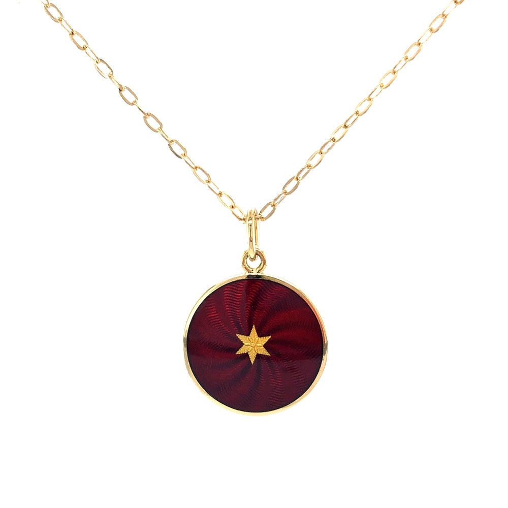 Kleiner runder Anhänger aus Gelbgold, etwa so groß wie eine kleine Münze. Die Vorderseite schimmert in transluzider auberginefarbener Emaille mit feinem Wellenmuster. In der Mitte liegt ein winziges sechseckiges Goldplättchen in Sternform mit mikroskopisch feinen Reliefdetails.