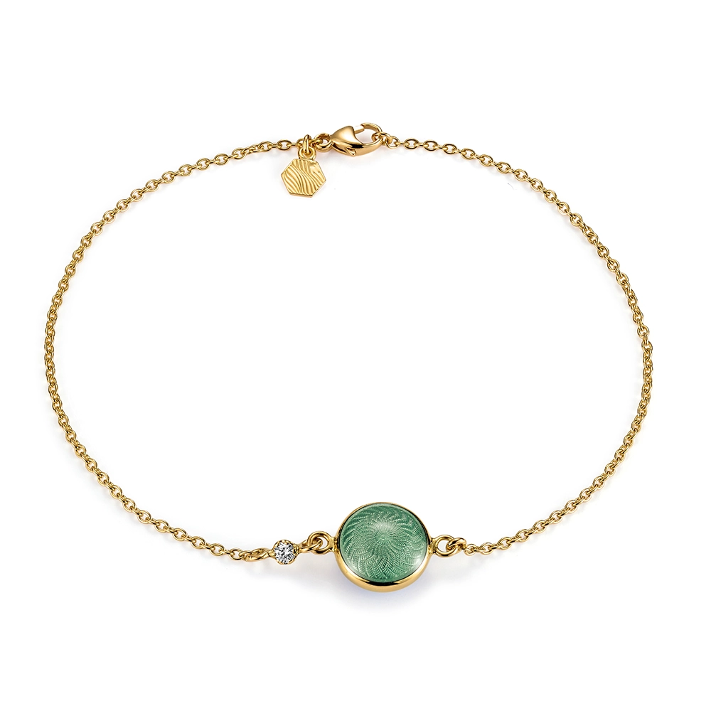 Candy bracelet in yellow gold featuring a double-sided, round, slightly domed central enamel element in translucent light green vitreous enamel over fine windmill guilloché, a sparkling diamond set into the anchor chain, and a guilloché hexagonal tag at the clasp, diameter 20.2 mm, length 19 cm.