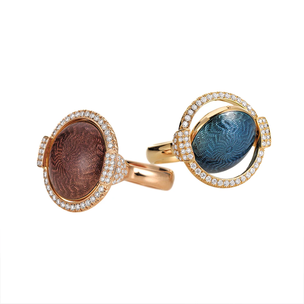 Drehbare Ringe Candy in Gold mit einer runden, gewölbten Mittellinse, die gedreht werden kann, um rosa oder purpur Emaille in einem Ring und blaues und helles Türkis im anderen Ring zu zeigen, verziert mit einem Windmühlen-Guilloché-Muster und umrahmt von 78 Diamanten, 20 x 22 mm.