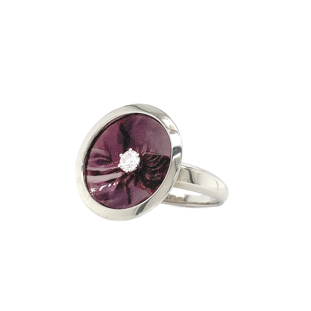 Ring in white gold with a round ring head. The ring head is concave and covered with translucent purple vitreous enamel, beneath which a fine windmill guilloché pattern is visible. A single small diamond is set at the centre of the enamel surface as a subtle focal point. The design appears calm, geometric, and balanced.