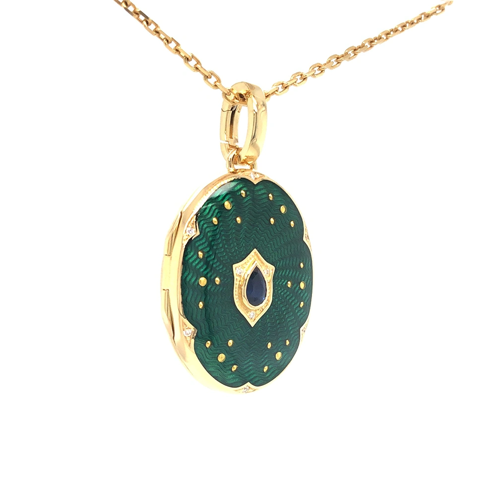 Ovaler Medaillon-Anhänger aus Gelbgold, grün lackiert mit zahlreichen kleinen Goldpunkten und mit einem tropfenförmigen blauen Edelstein in der Mitte.