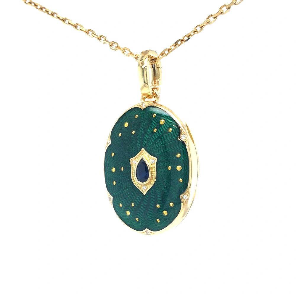 Ovaler Medaillon-Anhänger aus Gelbgold, grün lackiert mit zahlreichen kleinen Goldpunkten und mit einem tropfenförmigen blauen Edelstein in der Mitte.